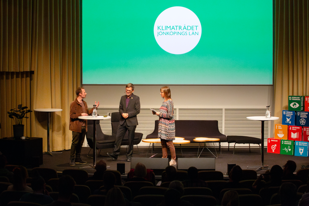 Peter Alestig, Mattias Goldmann tillsammans med klimatkonferensens moderator på scen.